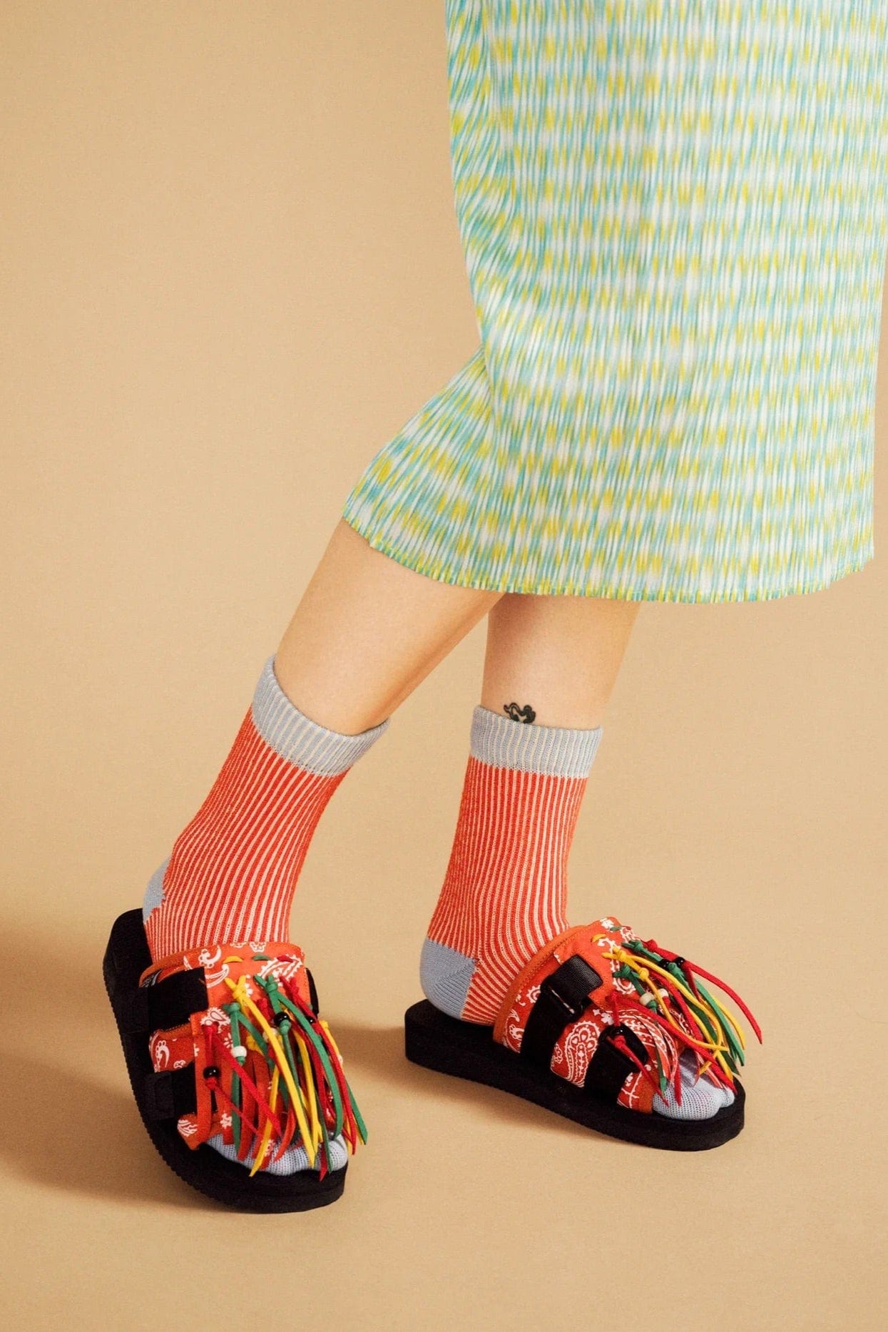 Person wearing colorful sandals and socks on a beige background